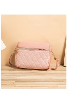 Detail of pink quilted cross-body bag with gold hardware on a wooden surface