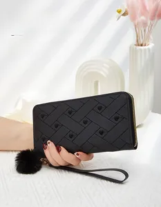 Dettaglio del portafoglio lungo nero ricamato con cuori, zip dorata e ciondolo a pompon