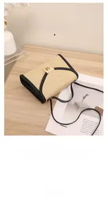 Detail of minimalist straw crossbody bag showing metal buckle and black leather trim