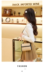 Detail of woven straw crossbody bag with black leather trim and gold metal fastener