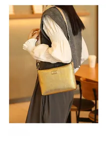 Golden envelope shoulder bag with chevron texture worn by a model in a cozy cafe