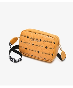 Detail of yellow quilted crossbody bag featuring a golden plaque and wide lettered strap