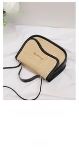 Detail of woven straw bag with black leather trim and gold metal logo on white fabric