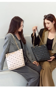 Close-up of quilted pattern tote bag with gold chain strap in beige and black