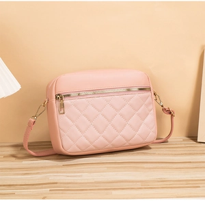 Detailed view of pink quilted crossbody bag featuring golden zippers and textured PU leather