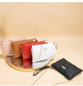 Detail view of five V-quilted small crossbody bags with gold chains on a mirror