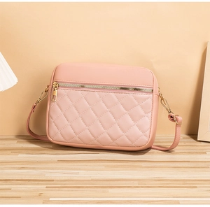 Close-up of pink quilted crossbody bag with gold zipper detail on a wooden table