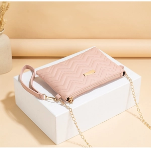 Detailed view of pink wavy quilted crossbody bag with gold chain strap and wristlet