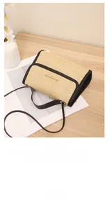 Close-up of straw woven crossbody bag with black leather trim and gold metal logo
