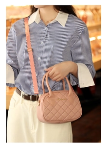 Close-up of pink quilted pillow bag with golden logo and adjustable shoulder strap