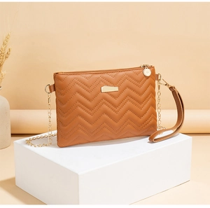 Detail of brown quilted faux leather bag with gold hardware on white pedestal