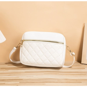 Detail of white quilted crossbody bag with gold zippers and polished hardware finish