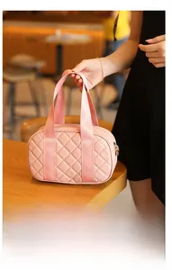 Detailed view of pink quilted Boston bag with diamond stitching on a cafe table