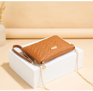 Detail of a brown chevron quilted crossbody bag with gold hardware on a display stand