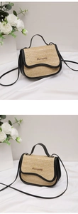Detail of woven straw handbag with contrast black leather trim and gold logo