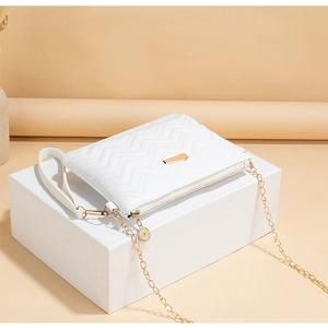 Detail of white wave quilted crossbody bag with gold chain strap on display stand