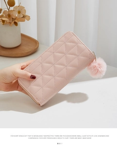 Détail du portefeuille long matelassé rose pour femme avec breloque pompon en fourrure