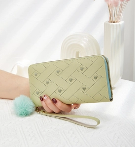 Dettaglio del portafoglio lungo verde chiaro con ricamo a cuore e pompon di peluche