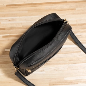 Chic black quilted crossbody camera bag with gold zipper and spacious interior compartment