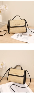 Detail of woven straw handbag with black leather trim and golden metal logo accent