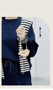 Detail of creative lip-shaped mini bag with metallic gold finish and slim chain strap