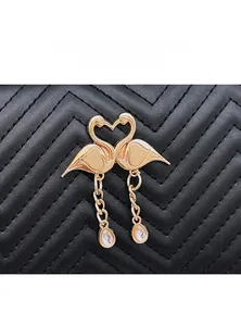 Detail of swan heart-shaped golden clasp with crystals on wave pattern quilted handbag