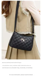 Detail of black quilted shoulder bag with golden bow and leather texture display
