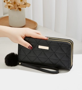 Détail du portefeuille long noir matelassé avec double fermeture éclair et pompon doux