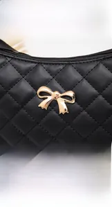 Detail of quilted leather texture and golden bow buckle on black shoulder bag