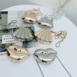 Detailed view of fashionable glossy lip and shell shaped mini chain bags in metallic colors