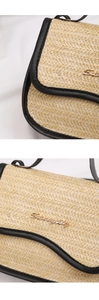 Detail of woven straw texture and gold logo on black leather trim of the saddle bag