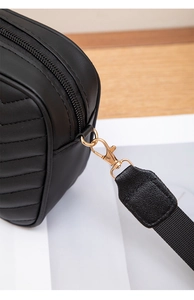 Close-up of black quilted leather camera bag with gold hardware and woven strap