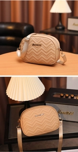 Détail du motif matelassé à vagues et logo doré sur le sac bandoulière beige minimaliste