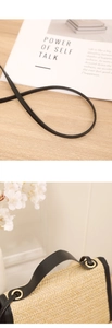Close-up of beige straw woven texture with black leather handle and gold hardware detail
