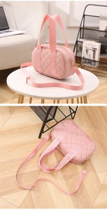 Close-up of pink quilted Boston bag with wide fabric straps and golden hardware details