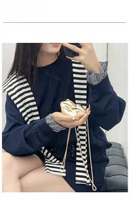 Golden lip-shaped clutch bag with sleek metal chain strap shown in a model pose