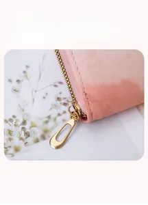 Nahaufnahme des goldener Metallreißverschlusses an der rosa Damen-Brieftasche