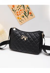 Detailed close-up of a black quilted bag featuring a golden bow metal accessory on top