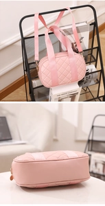 Detail of pink quilted Boston bag with nylon webbing handles and gold hardware