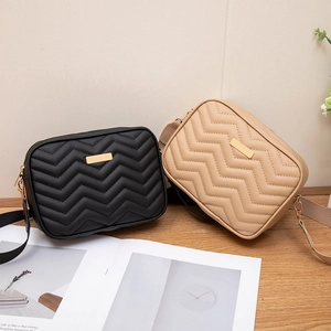 Black and beige wave-quilted crossbody bags with gold metal plates and zip top closure