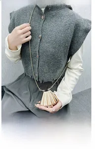 Detail of a gold metallic shell clutch bag with vertical pleats and chain strap