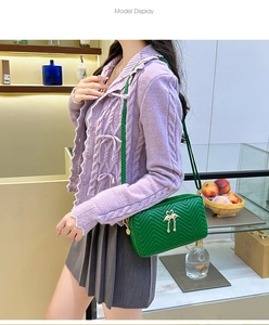 Detail of green chevron quilted crossbody bag with golden flamingo charms on a model