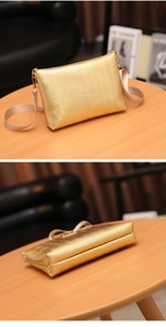 Detail of gold chevron texture crossbody bag with adjustable beige strap on wooden table