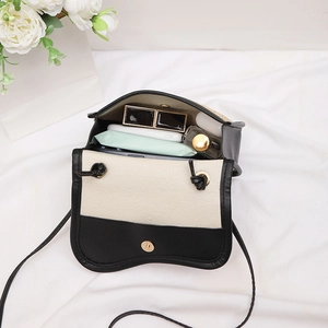 Black and white woven saddle bag showing interior capacity for phone and cosmetics