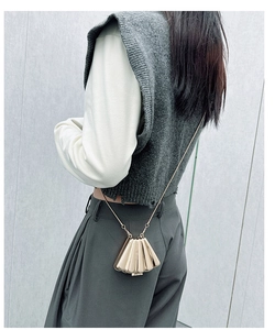 Chic gold shell-shaped mini bag with chain strap shown on a model for scale and style