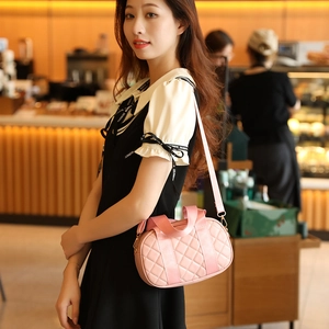 Pink quilted Boston shoulder bag with wide strap shown in a warm cafe lifestyle setting