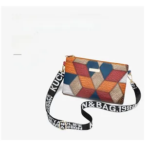 Detail of color-block crossbody bag with pebbled texture and wide letter-printed strap