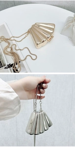 Detailed view of metallic shell-shaped evening bag with textured surface and gold chain