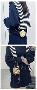 Dettaglio mini borsa a fiore dorata con catena in metallo su felpa blu navy