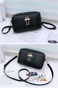 Detailed view of the wave-quilted black crossbody bag with golden swan emblem and tassel